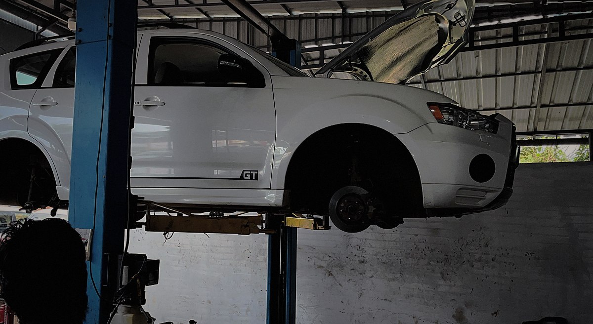 A Mitsubishi Outlander raised on the lift with a wheel off, mid-service